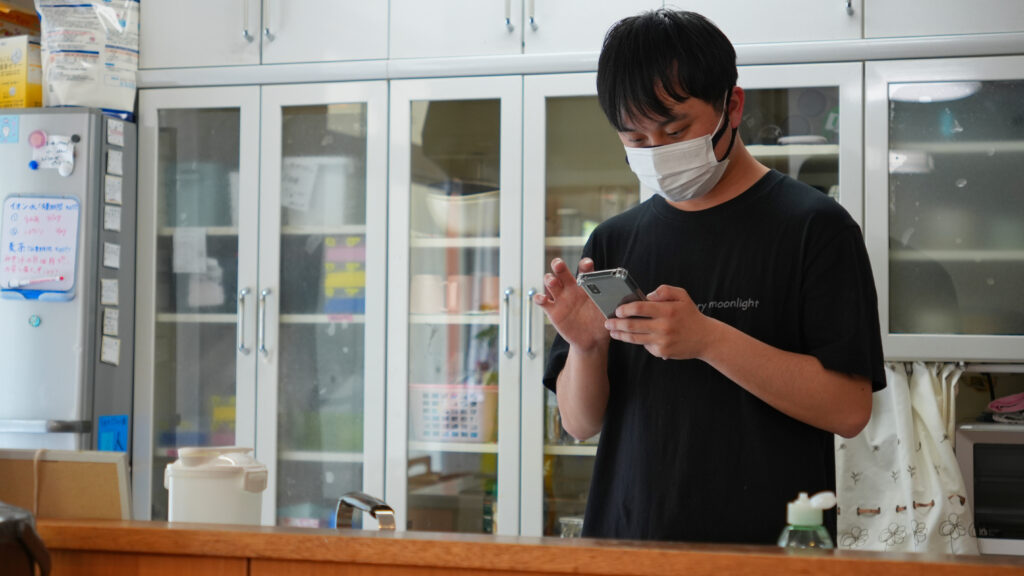 スタッフさんがスマホでケアコラボを操作している写真