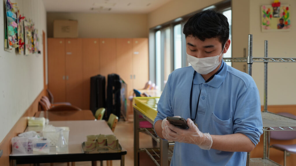 現場スタッフさんがスマホでケアコラボを操作する写真