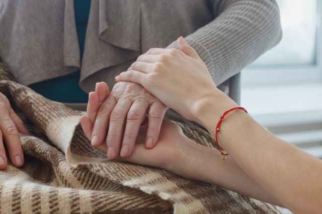 ご高齢者と介護スタッフが手を握り、タッチングをしている写真
