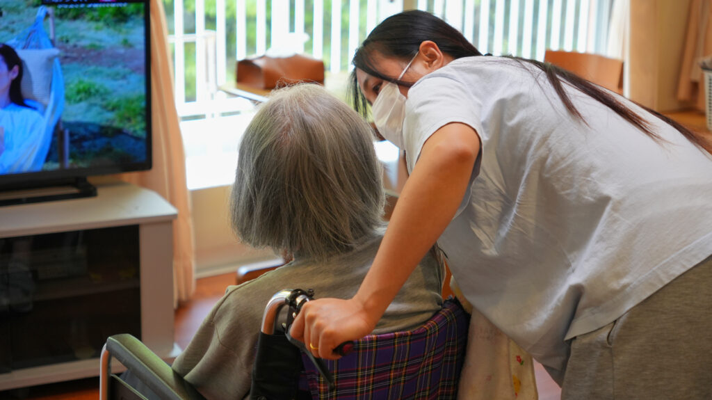 元気なご利用者の車いすを、介護スタッフが押しながら会話をしている写真