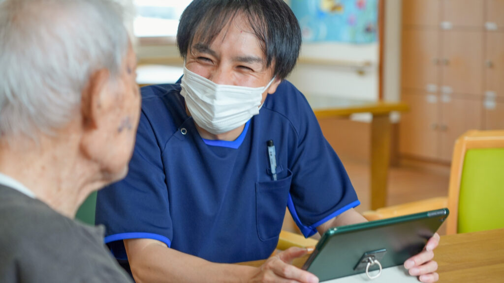 元気なご利用者と介護スタッフが、笑顔で会話をする写真