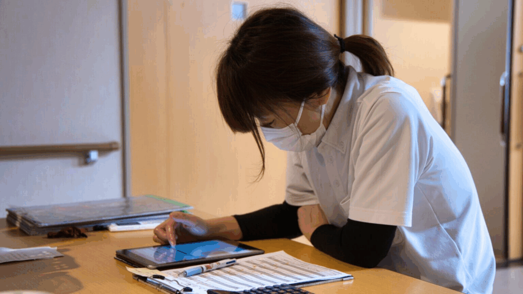 介護現場でその場でタブレットで記録を入力している写真