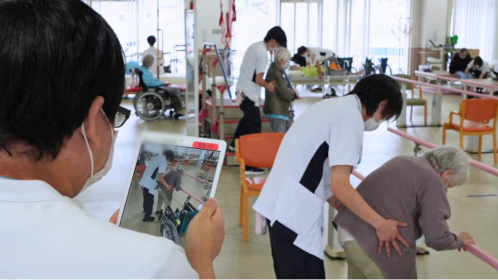 機能訓練指導員がタブレットを使いリハビリの様子を動画で撮影しているところ