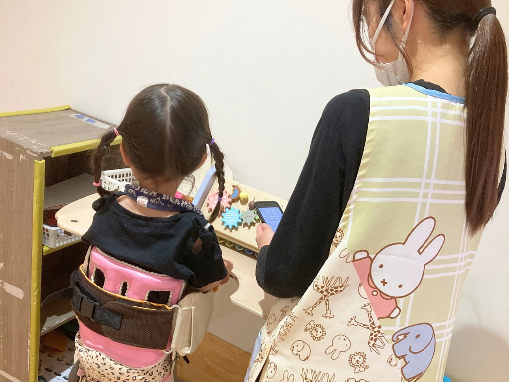 赤塚さんがスマホでケアコラボを見ている写真